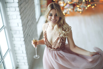 Party, drinks, holidays, people and celebration concept - smiling woman in beautiful dress with glass of sparkling wine and champagne over Christmas tree lights background. High quality photo.