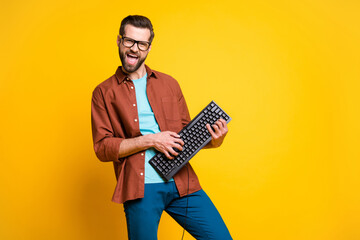 Photo portrait of bearded man keeping keyboard playing like guitar isolated on bright yellow color background