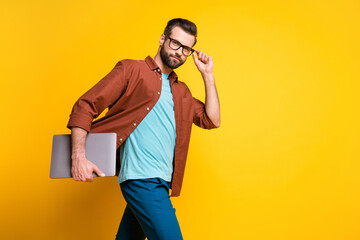 Photo of young handsome man go walk confident serious hold laptop isolated over yellow color background
