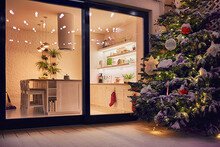 Cozy Apartment With Sliding Doors, And Decorated Christmas Tree On The Patio At Snowy Winter Night