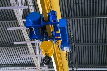 Overhead traveling cathead with steel hooks in industrial engeenering plant shop. Steel slings. Side view.