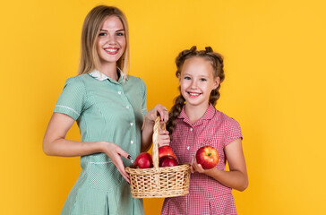 Wall Mural - happy girl and mother holding apples from garden. kid hold basket with fruit. mom and child eating apple. summer healthy food. vegetarian dieting. fruits at fall harvest. Healthy nutrition in autumn