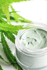  Green cannabis plant and jar with a moisturizing cream