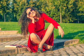 beautiful young brunette girl in red dress in green park