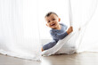 © Lisa Tichané - Happy baby peeking behind curtains at home