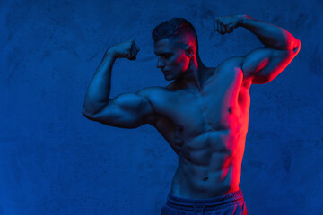 Muscular man posing in the colorful light