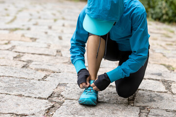 Wall Mural - woman runner tying shoelace on trail