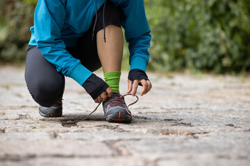 Wall Mural - woman runner tying shoelace on trail