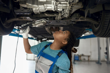 Wall Mural - Young afro american girl looking at bottom of car