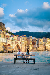 Wall Mural - couple on vacation Sicily visiting the old town of Cefalu,sunset at the beach of Cefalu Sicily, old town of Cefalu Sicilia panoramic view at the colorful village.Italy