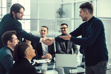 Wall Mural - smiling business people shaking hands over an office Desk