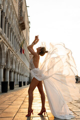 Woman wearing beautiful white dress walking on a street of the Venice city