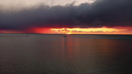 Wall Mural - Beautiful panning in aerial of the Ludington Breakwater Lighthouse with the sun reflecting on the water of Lake Michigan and lighting up the sky and clouds with colorful pink, orange and yellow.