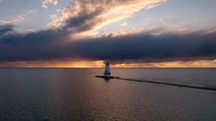 Wall Mural - Beautiful sunset aerial hovering in front of the white colored Ludington breakwater lighthouse with blue and orange sky and clouds above reflecting on the water of Lake Michigan.