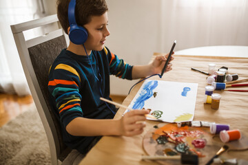 Cute little boy painting a picture in home studio