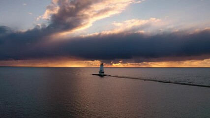 Wall Mural - Beautiful sunset aerial panning in front of the white colored Ludington breakwater lighthouse with blue and orange sky and clouds above reflecting on the water of Lake Michigan.