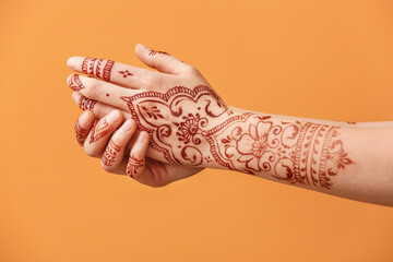 Wall Mural - Beautiful female hands with henna tattoo on color background