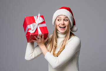 Young woman keeps a christmas gift in white paper isolated gray background