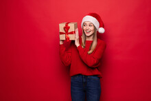 Christmas Woman Holding Christmas Gifts Smiling. Cute Beautiful Caucasian Santa Woman Isolated On Red Background
