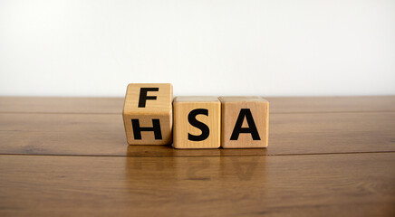 FSA or HSA symbol. Turned a cube and changed the word 'FSA - Flexible Spending Account' to 'HSA - Health Savings Account'. Beautiful wooden table. White background. Business and FSA or HSA concept.