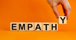 Empathy symbol. Concept word 'empathy' on wooden cubes on a beautiful orange background. Male hand. Psychological and empathy concept, copy space.