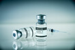 © daboost - Covid-19 vaccine bottle and syringe on a blue background