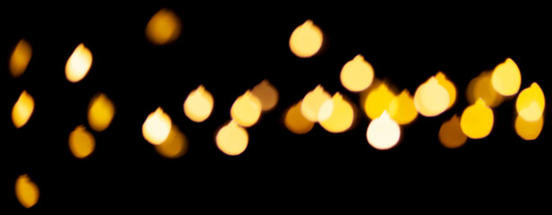 Yellow Christmas decorations bokeh lights on a black background. Abstract shiny pattern in defocus.