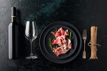 Wall Mural - Prosciutto and rosemary on a black plate.