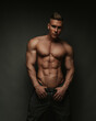 © Serge Lee - Shirtless handsome young guy in pants standing in studio at grey background