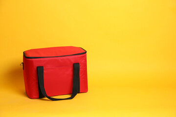 Modern red thermo bag on yellow background. Space for text