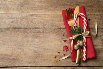 Cutlery set and festive decor on wooden table, flat lay with space for text. Christmas celebration