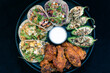 Overhead view of delicious appetizer sampler plate with chicken and steak tacos, poppers, and buffalo wings makes the mouth water and the stomach growl.