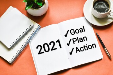 2021 New Year. Goal,plan, action text on notepad with office accessories on pink background. Business motivation, inspection concepts ideas.