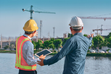 Two people worker Engineer talking discussion by tablet on site building real estate construction