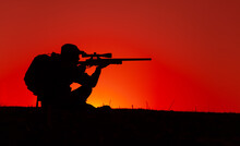 Commando Team Sniper, Army Special Forces Shooter Aiming, Shooting Sniper Rifle While Sitting On Sea Or Ocean Shore During Sunset. Coast Or Border Guard Soldier Observing Coastline With Optical Sight