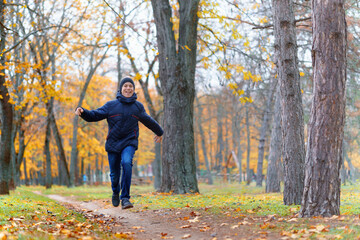 Wall Mural - a boy running through the park and enjoys autumn, beautiful nature with yellow leaves