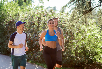 Sticker - Group of young people in sports clothing running in city park.