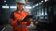 © Gorodenkoff - Professional Heavy Industry Engineer/Worker Wearing Safety Uniform and Hard Hat Uses Tablet Computer. Serious Successful Female Industrial Specialist Standing in a Metal Construction Manufacture.