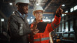 © Gorodenkoff - Two Heavy Industry Engineers Stand in Steel Metal Manufacturing Factory, Use Digital Tablet Computer and Have a Discussion. Black African American Industrial Specialist Talk to Female Technician.