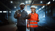 © Gorodenkoff - Two Heavy Industry Engineers in Hard Hats Walk in Steel Metal Manufacturing Factory and Have a Discussion. Black African American Industrial Specialist Talk to Female Technician in Manufacture.
