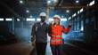 © Gorodenkoff - Two Heavy Industry Engineers in Hard Hats Walk in Steel Metal Manufacturing Factory and Have a Discussion. Black African American Industrial Specialist Talk to Female Technician in Manufacture.