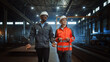 © Gorodenkoff - Two Heavy Industry Engineers in Hard Hats Walk in Steel Metal Manufacturing Factory and Have a Discussion. Black African American Industrial Specialist Talk to Female Technician in Manufacture.