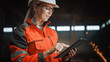 © Gorodenkoff - Professional Heavy Industry Engineer/Worker Wearing Safety Uniform and Hard Hat Uses Tablet Computer. Serious Successful Female Industrial Specialist Standing in a Metal Manufacture Warehouse.