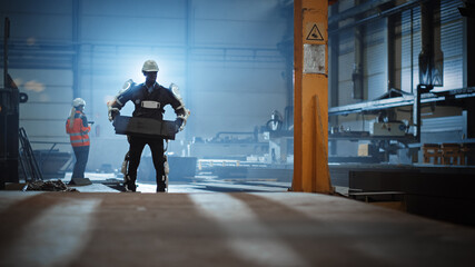 Poster - Black African American Engineer is Testing a Futuristic Bionic Exoskeleton and Carries Metal Object in a Heavy Steel Industry Factory. Contractor is Heavy Lifting Steel Parts in a Powered Shell.