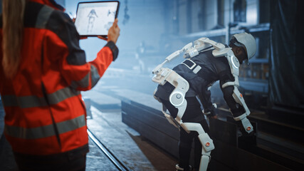 Aufkleber - Female Engineer is Testing Vital Components of a Futuristic Bionic Exoskeleton that Her Project Assistant is Wearing in a Metal Industry Factory. Contractor is Lifting Steel Parts in a Powered Shell.