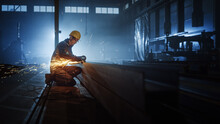 Heavy Industry Engineering Factory Interior With Industrial Worker Using Angle Grinder And Cutting A Metal Tube. Contractor In Safety Uniform And Hard Hat Manufacturing Metal Structures.