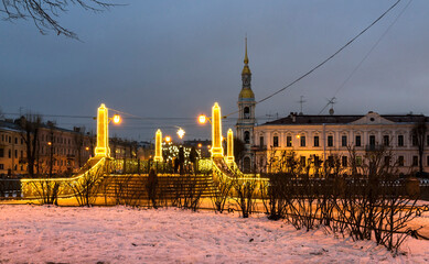 Saint Petersburg in Christmas holidays. People rest and walk around the festively decorated city, Krasnogvardeysky Bridge over the Griboedov Canal in the New Year's illumination. Festive cityscape