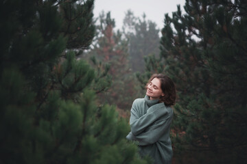 Wall Mural - Young beautiful happy woman walking in fir forest enjoying nature meditating outdoors