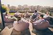 Nice attractive stylish partners sitting in bag chairs discussing company corporate project strategy plan on roof outside outdoor sunny day