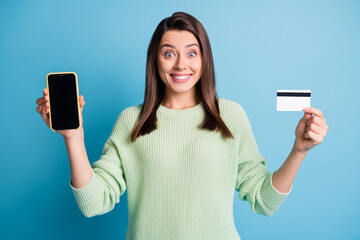 Wall Mural - Photo portrait of excited woman holding debit card phone with blank space isolated on pastel blue colored background